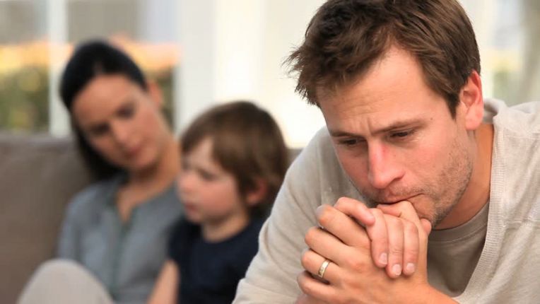 man looking worried, woman and child in background